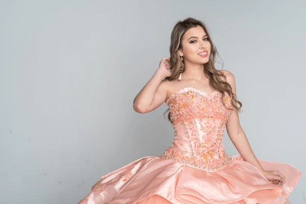 Teen girl posing in a sparkling pink quinceañera ball gown