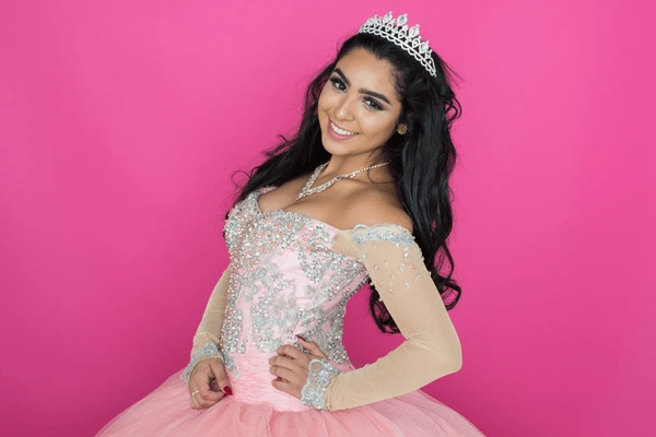 Smiling quinceañera wearing a jeweled pink dress and silver tiara