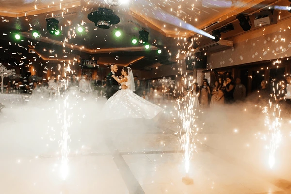 Bride and groom dancing while cold spark fountains illuminate the wedding floor