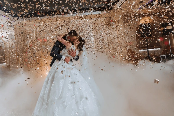 Bride and groom embracing during their first dance as confetti fills the air