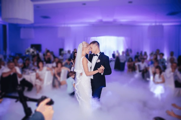 Bride and groom sharing their first dance with purple uplighting and low fog
