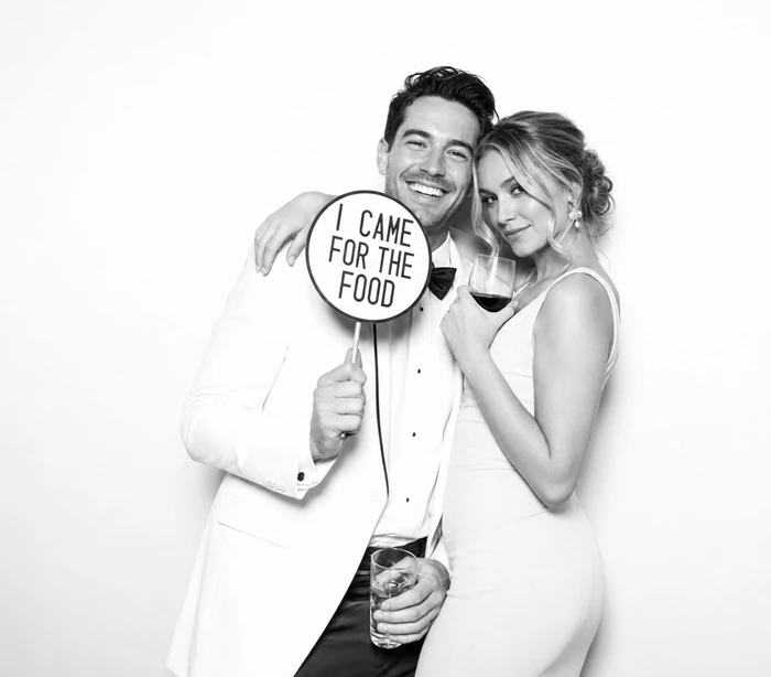 Wedding couple posing together with a funny food-themed photo booth sign